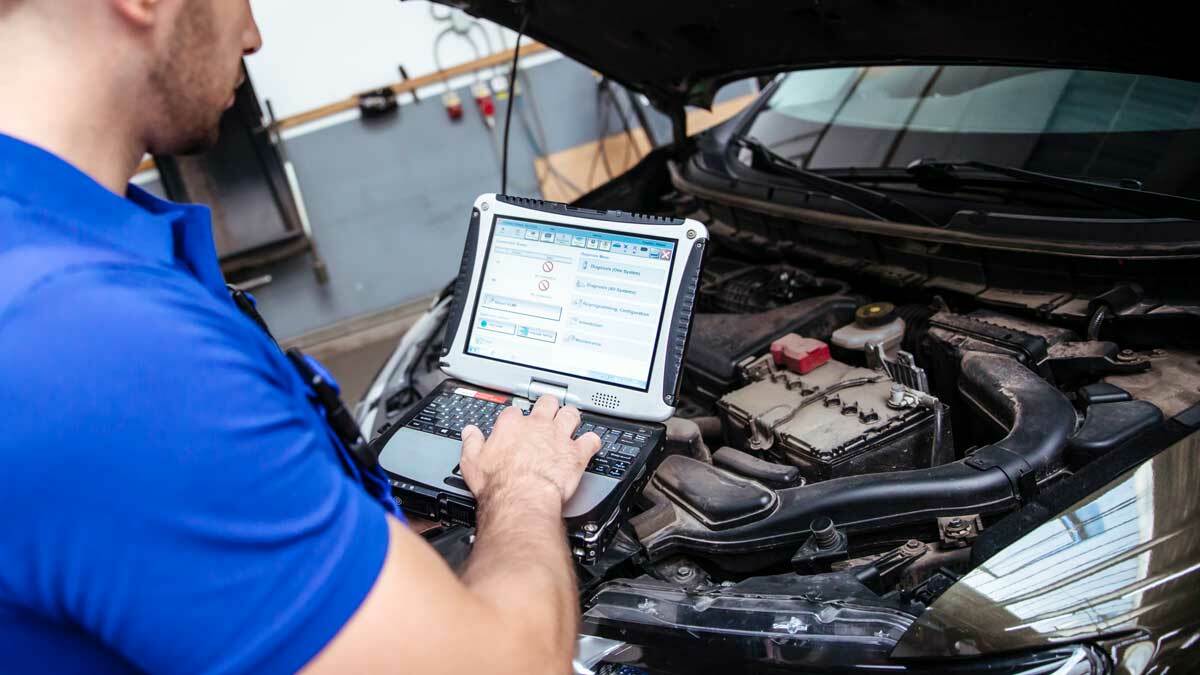 Mechaniker analysiert die Ergebnisse der Fahrzeugdiagnose am Bildschirm.