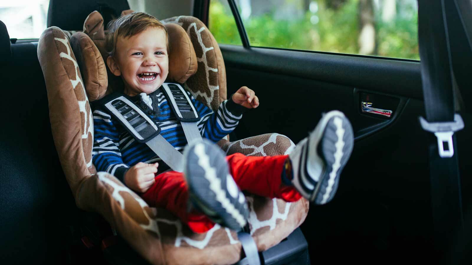 Lächelndes Baby sicher und komfortabel in einem Kindersitz im Familienauto sitzend